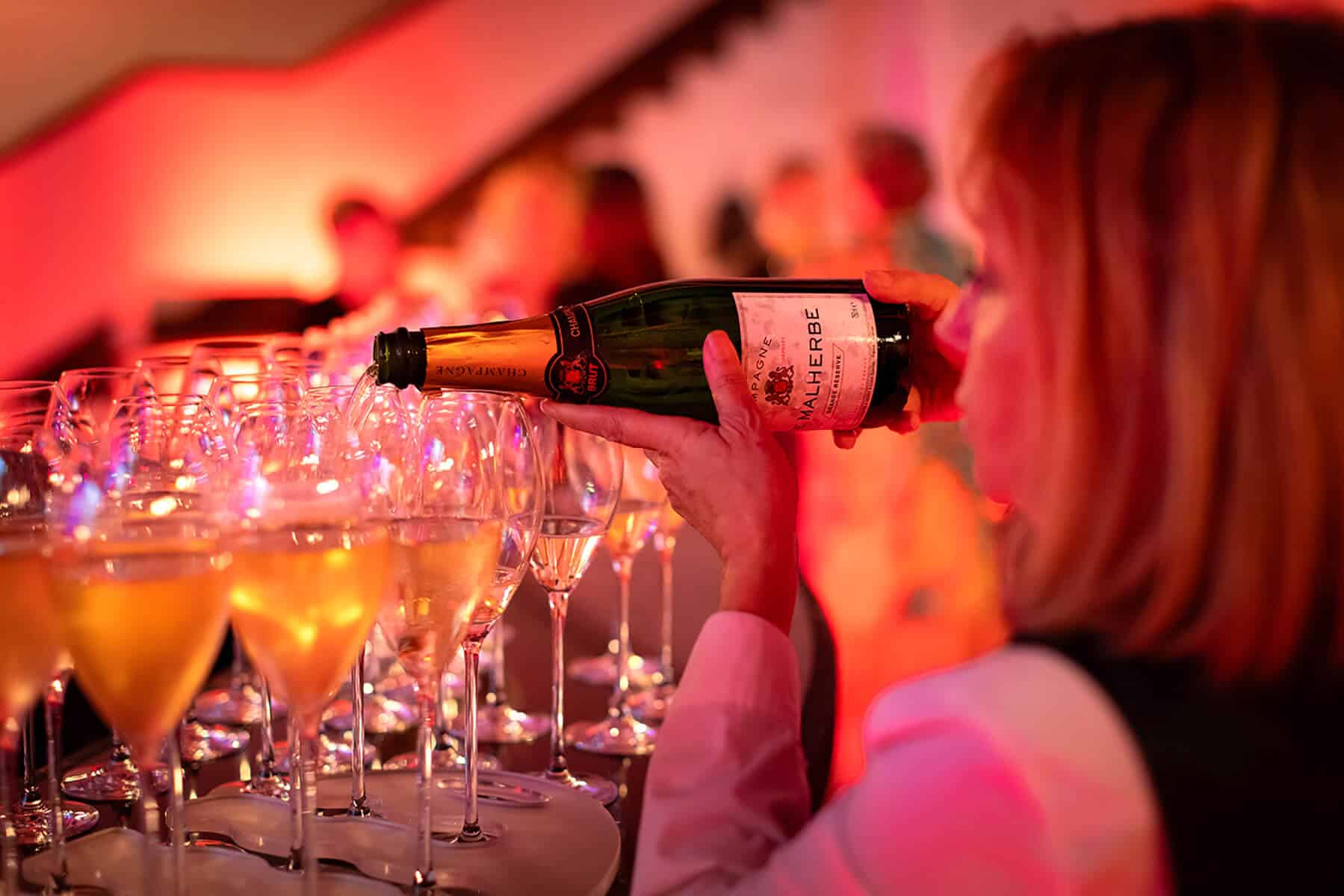 Champagne being poured into glasses at an evening event