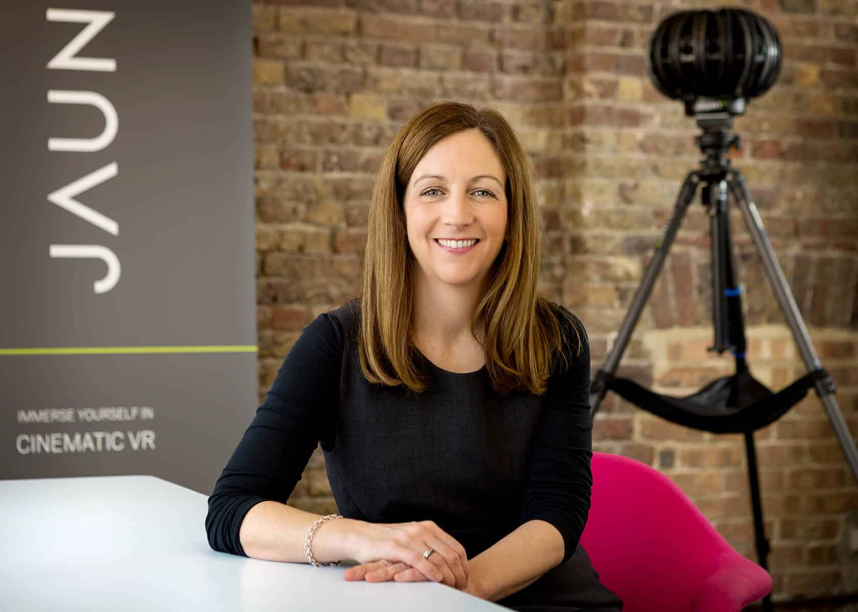 Professional woman seated beside a cinematic VR camera
