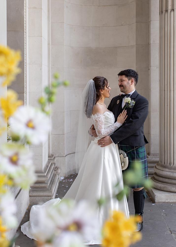 Wedding couple smiling together beside stone columns