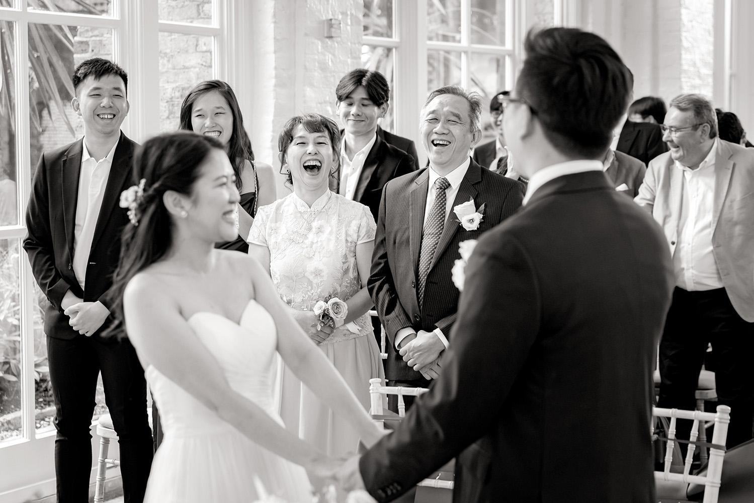 Bride and groom laughing with guests during an indoor wedding ceremony